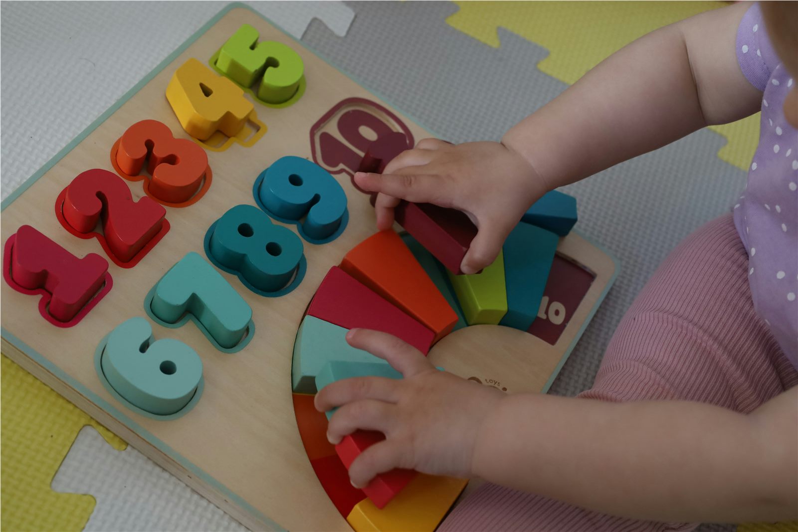 Infant exploring wooden Montessori number puzzle